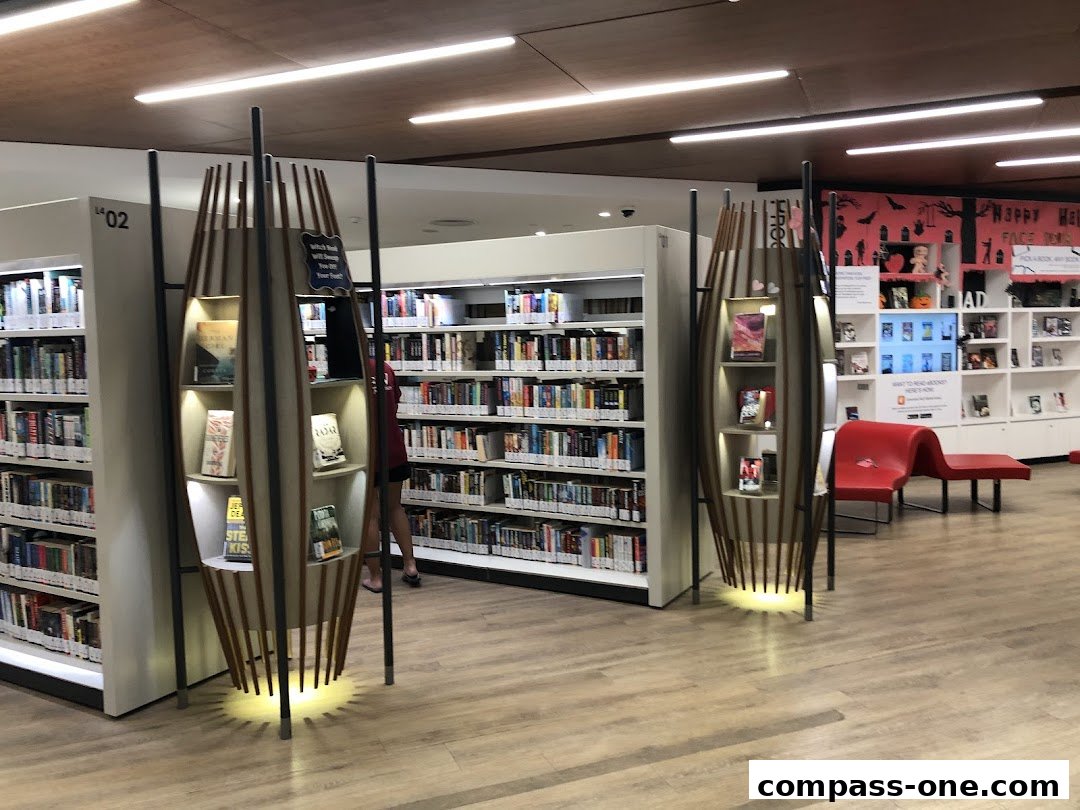 Interior view of a library with bookshelves, display stands, and seating.