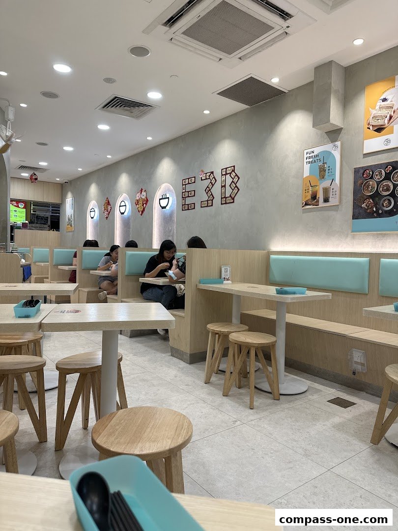 Interior view of a modern restaurant with light wood tables, stools, and light blue seating.