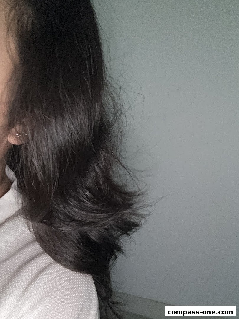 A close-up shot of a person's dark, layered hair with a light-colored garment.