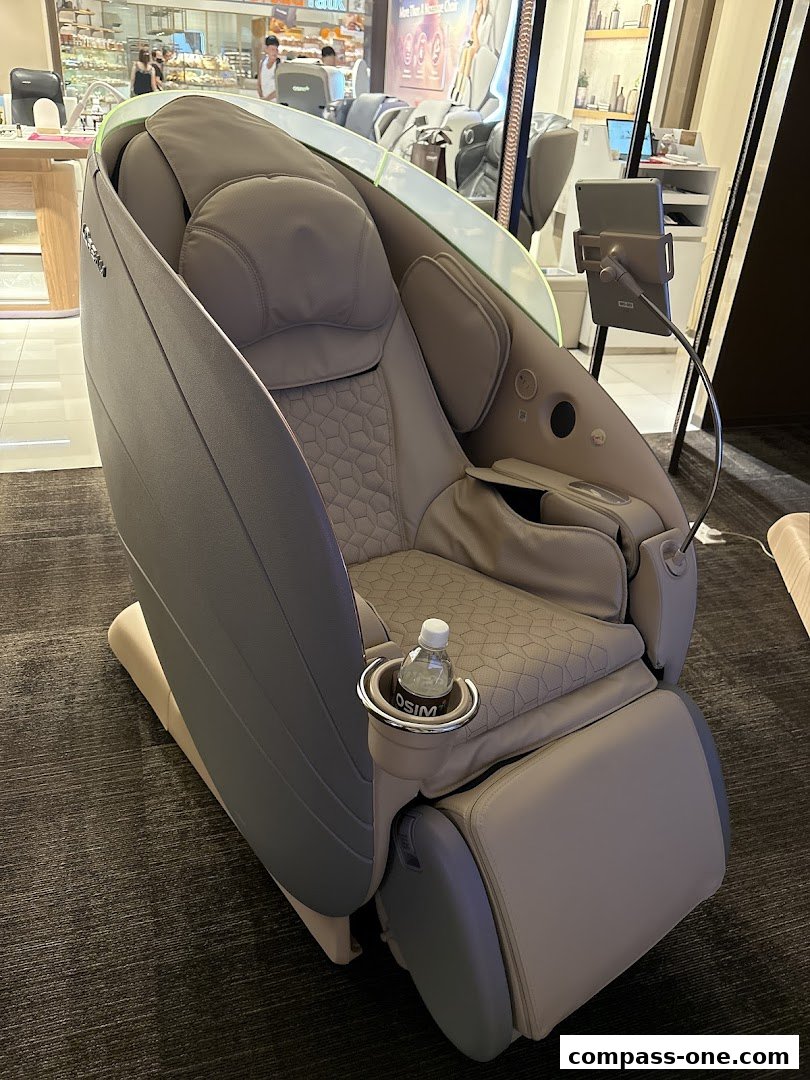 A modern, comfortable OSIM massage chair with a bottle of water in the cup holder.
