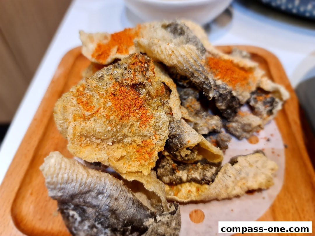 Crispy fried fish skin snacks seasoned with chili powder on a wooden plate.