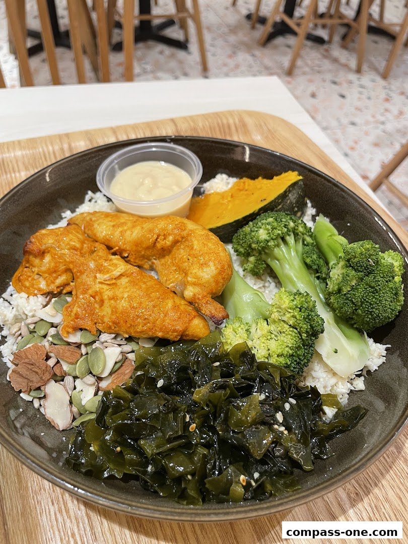 A healthy bowl with chicken, rice, vegetables, and seaweed.