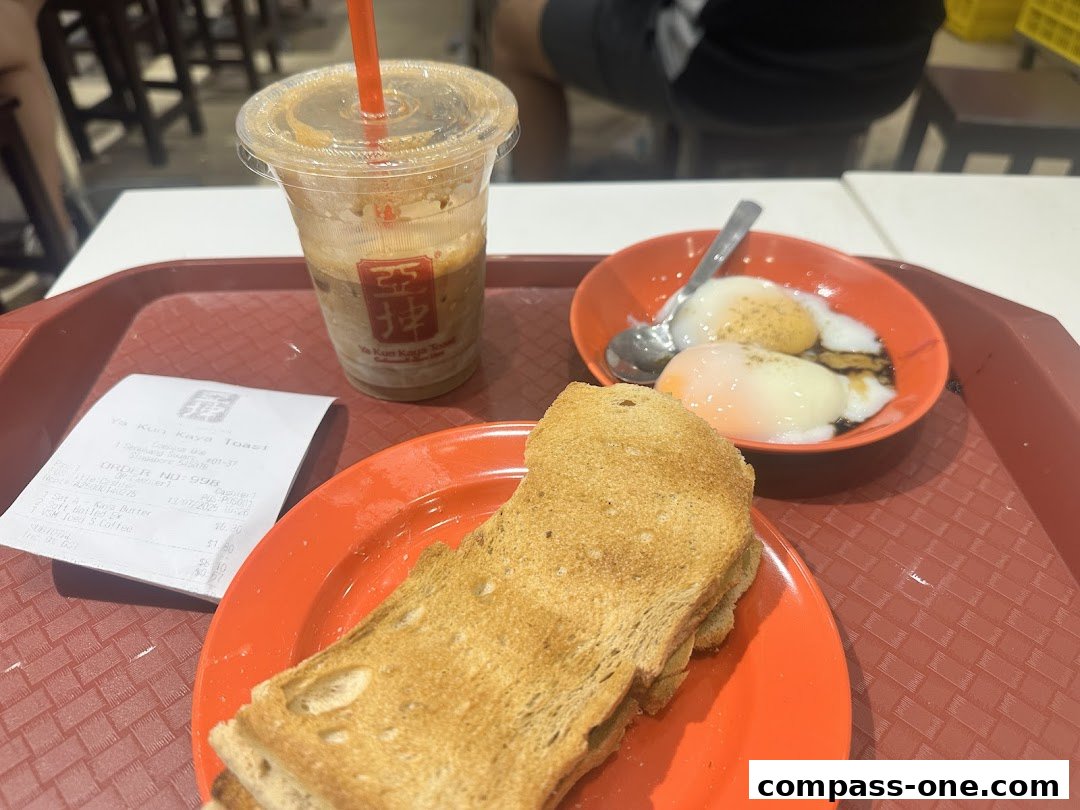 A tray with Ya Kun Kaya Toast's signature kaya toast, soft-boiled eggs, and iced coffee.