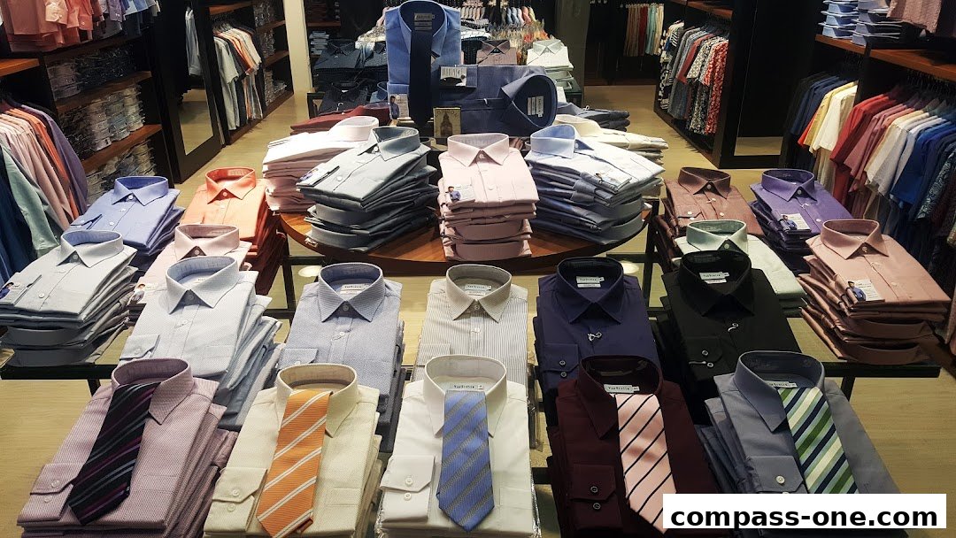 Neatly folded dress shirts and ties are displayed on tables and shelves in a retail store.