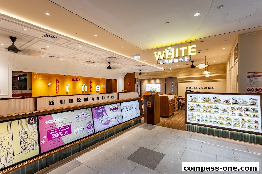 The interior of a brightly lit restaurant with a prominent "WHITE" sign and digital displays showcasing food.
