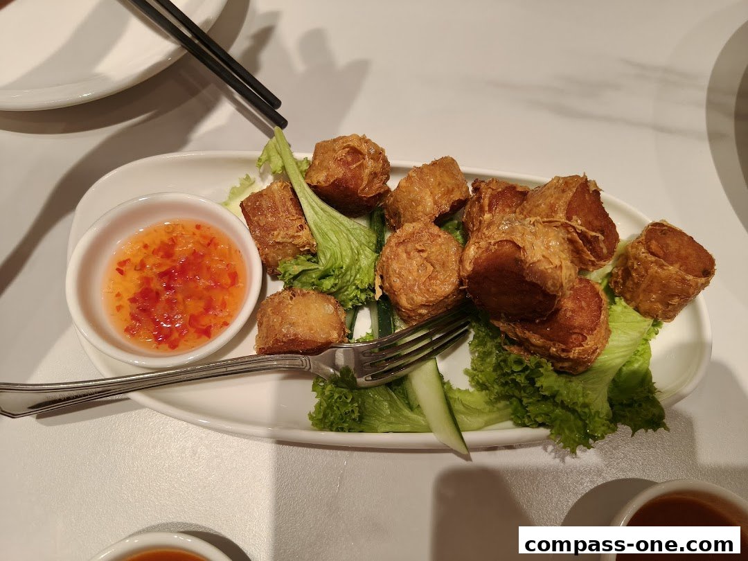A plate of crispy fried spring rolls served with sweet chili sauce and lettuce.