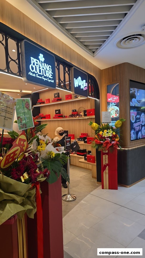 The entrance of a WOKE Ramen shop with 'Penang Culture' signage and festive decorations.
