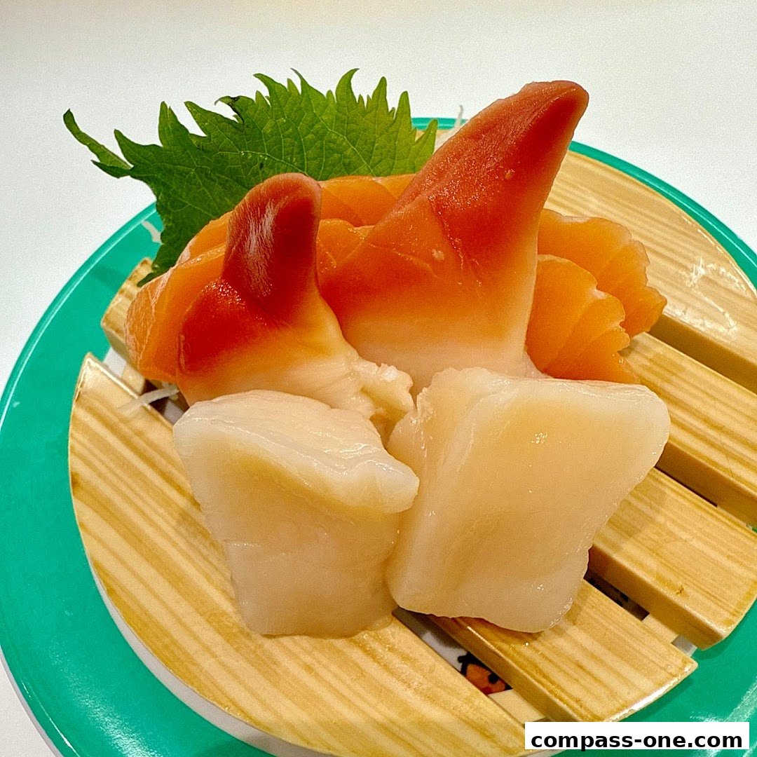 A close-up of fresh sashimi, featuring scallops and geoduck clam, artfully arranged.