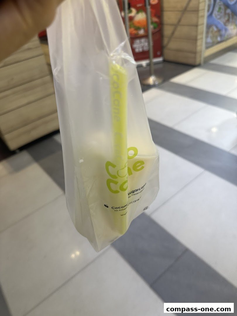 A person holding a plastic bag with a sugarcane drink and straw from CocoCane.