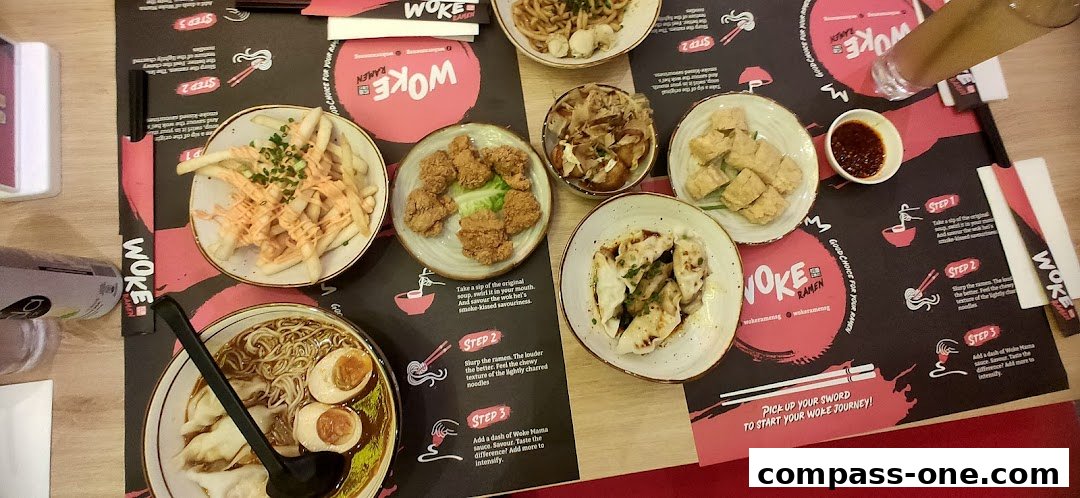 A table laden with various Woke Ramen dishes, including ramen, fried chicken, fries, dumplings, and tofu.