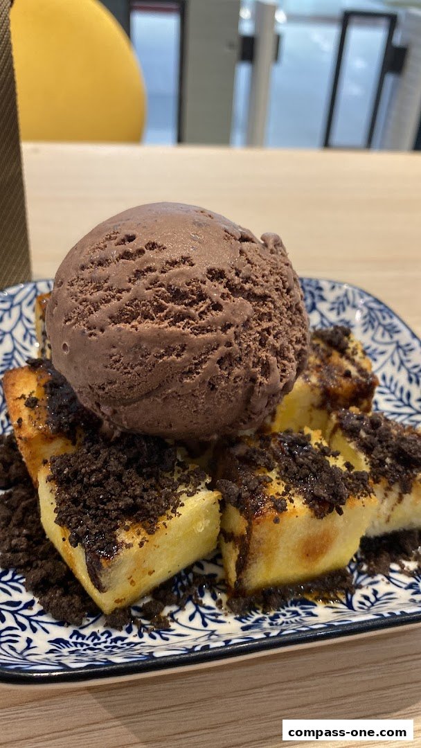 A close-up of a dessert with toast, ice cream, and cookie crumbs on a decorative plate.