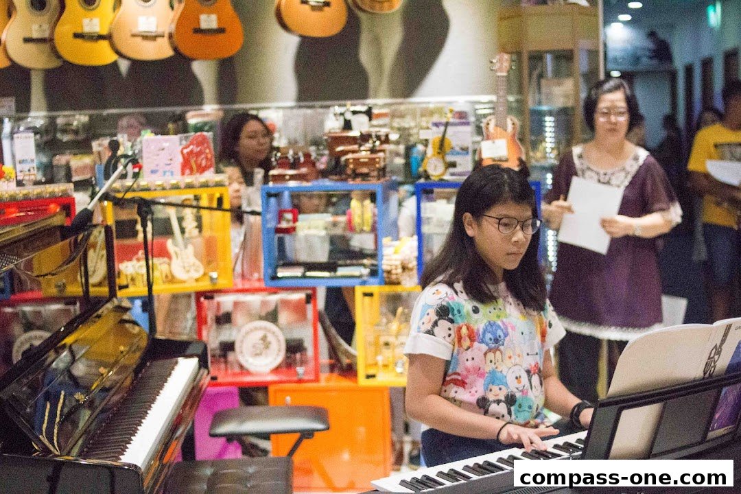 A young girl plays a keyboard in a music shop with guitars displayed above.
