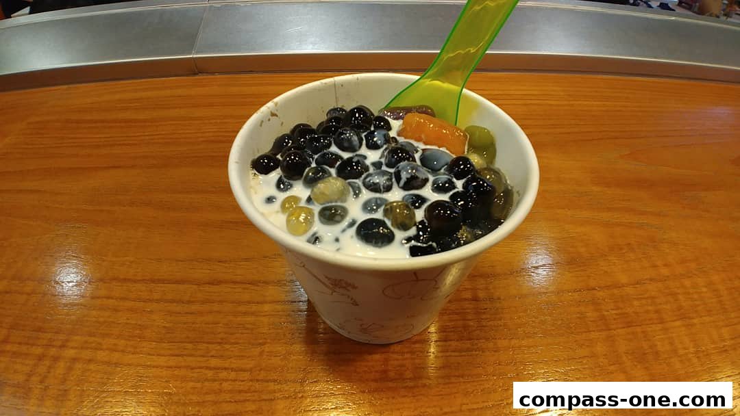A cup of Nine Fresh Desserts with various toppings and a green spoon.