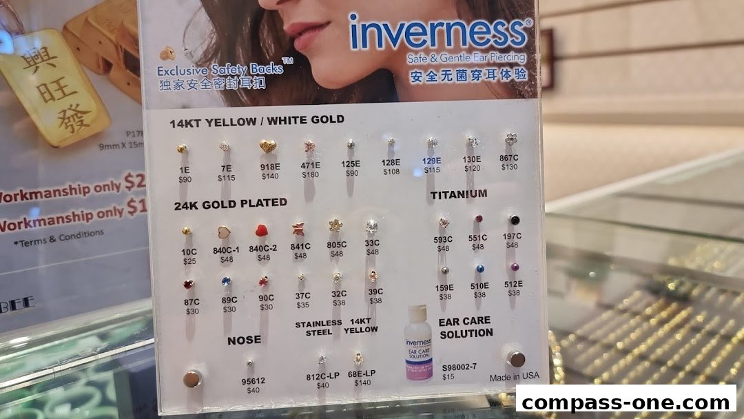 A display board showcasing various gold and titanium earrings with prices and product codes.