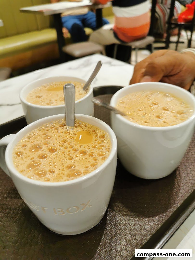 Three cups of frothy tea are served on a tray at Toast Box.