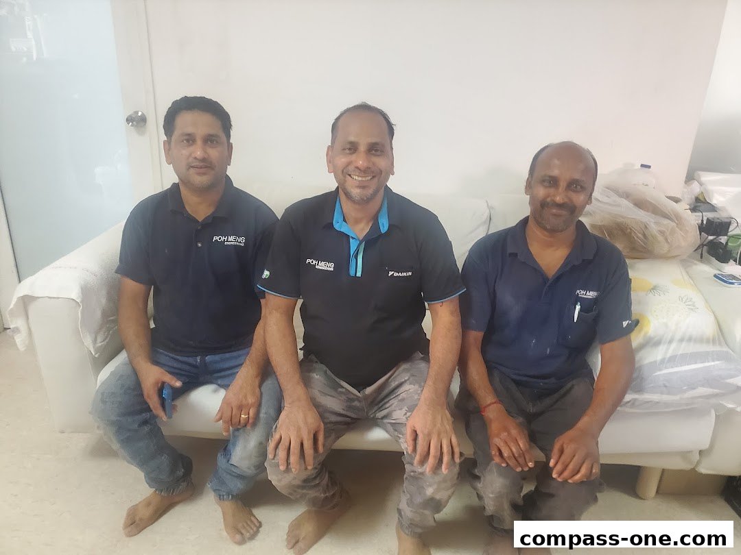 Three men in uniform sitting on a white couch, smiling at the camera.