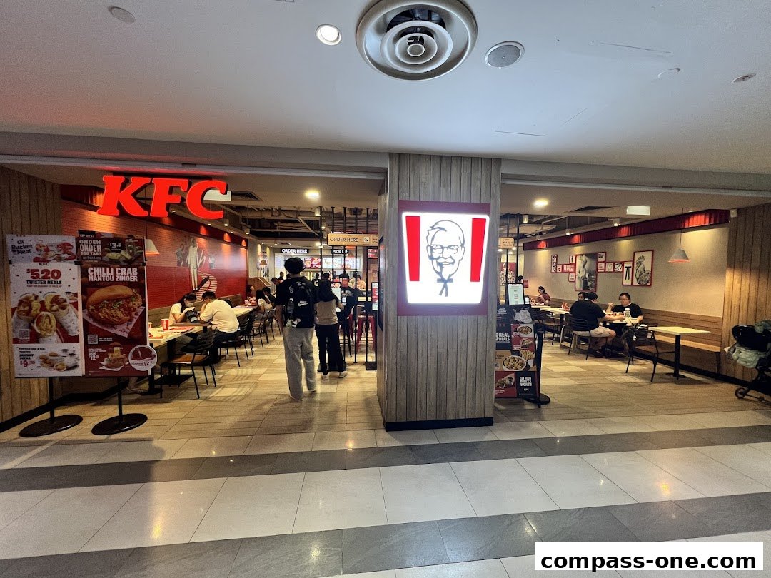 Interior view of a KFC restaurant with customers dining and a prominent KFC logo.
