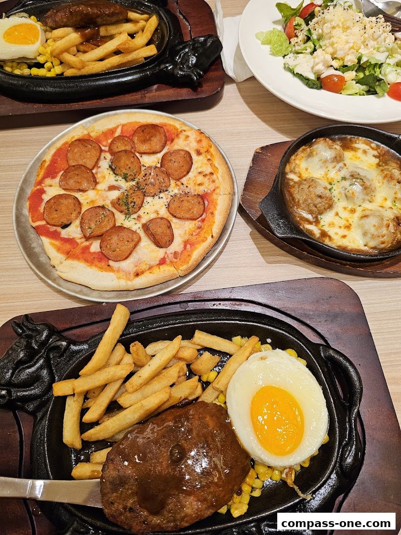 A table laden with various dishes including a pizza, steak with fries and egg, and meatballs.