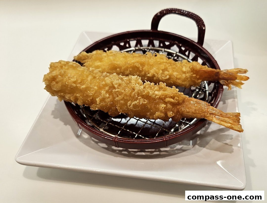 Two golden-brown, crispy fried shrimp are presented on a wire rack.