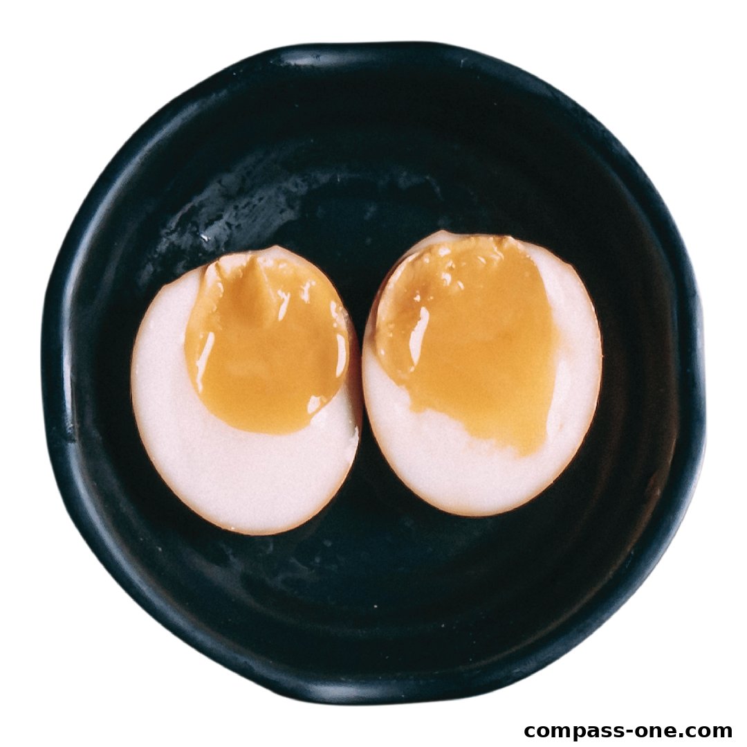 A close-up shot of two halves of a soft-boiled egg with a runny yolk in a dark bowl.