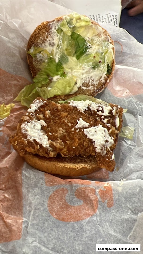 A close-up of a Burger King chicken sandwich with lettuce and sauce.