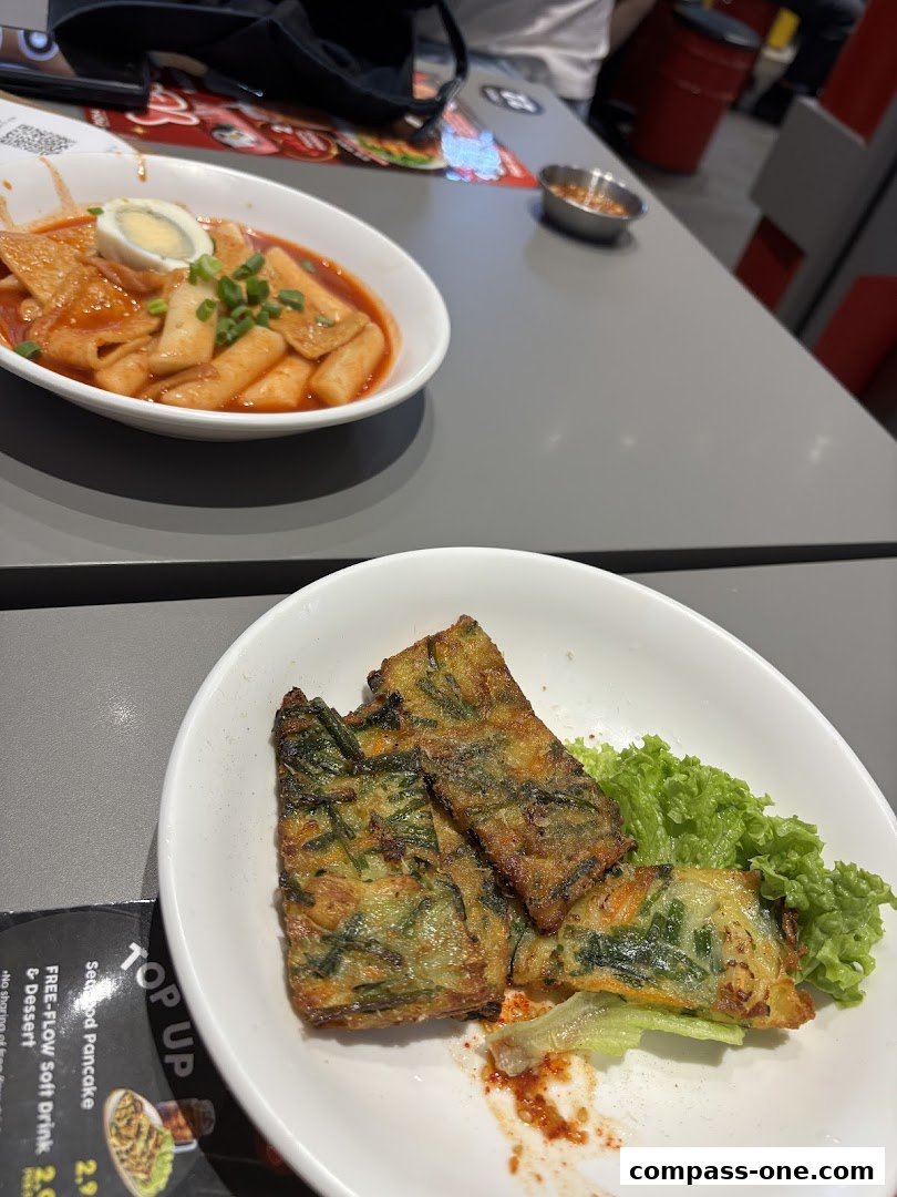 Two bowls of Korean street food, one with tteokbokki and the other with savory pancakes.