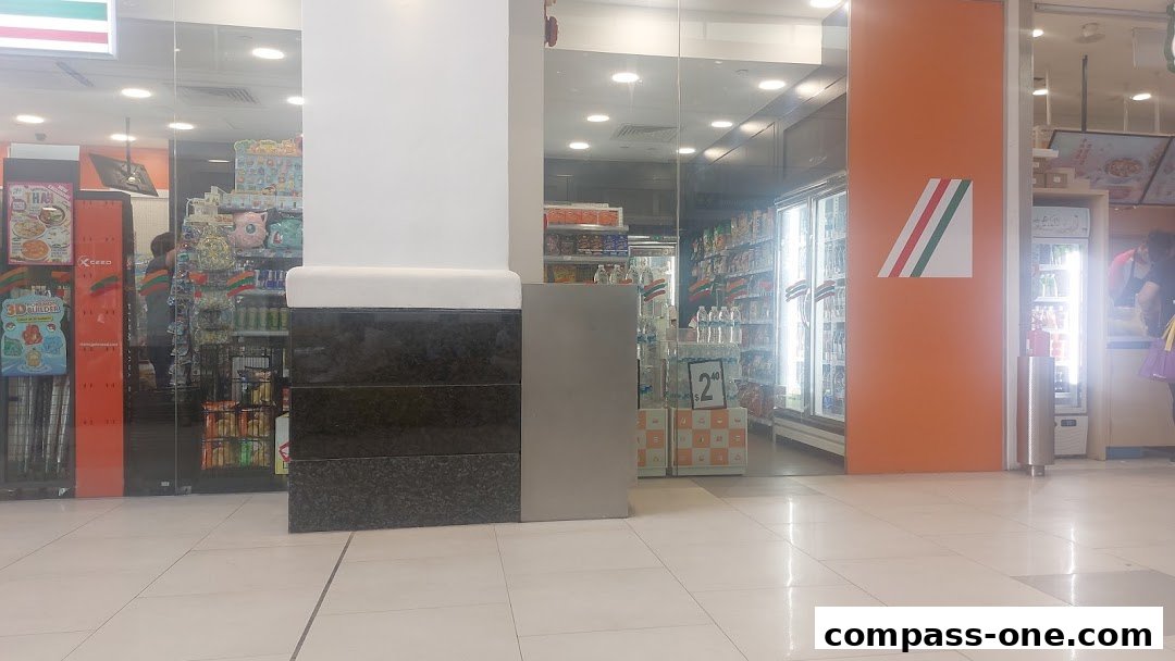 The entrance of a 7-Eleven convenience store with brightly lit refrigerators and shelves stocked with products.