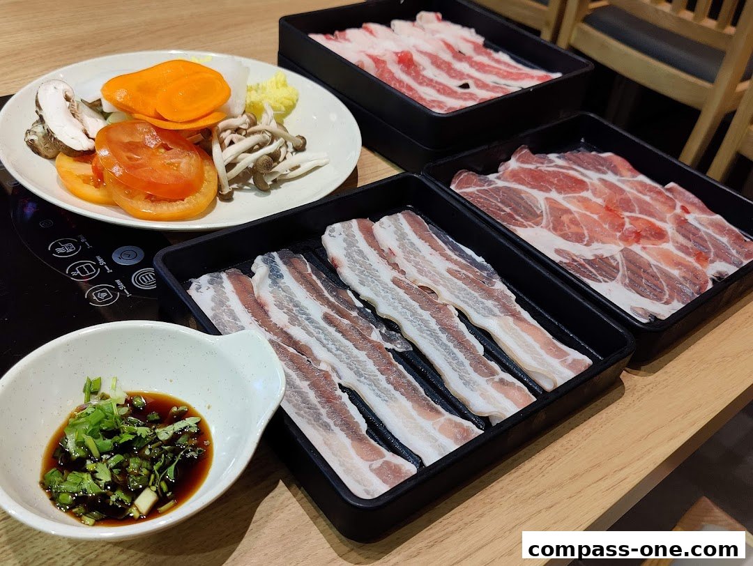 A table setting with fresh ingredients for shabu-shabu, including various meats and vegetables.