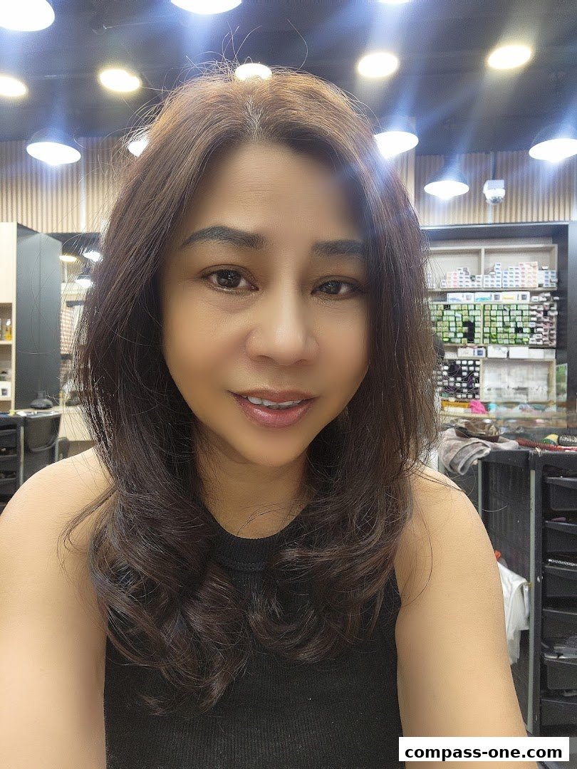 A woman with brown hair smiles at the camera in a brightly lit salon.
