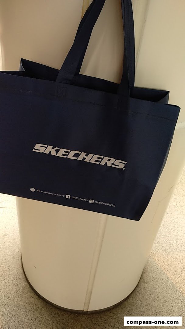 A dark blue Skechers shopping bag with the brand logo and website details.