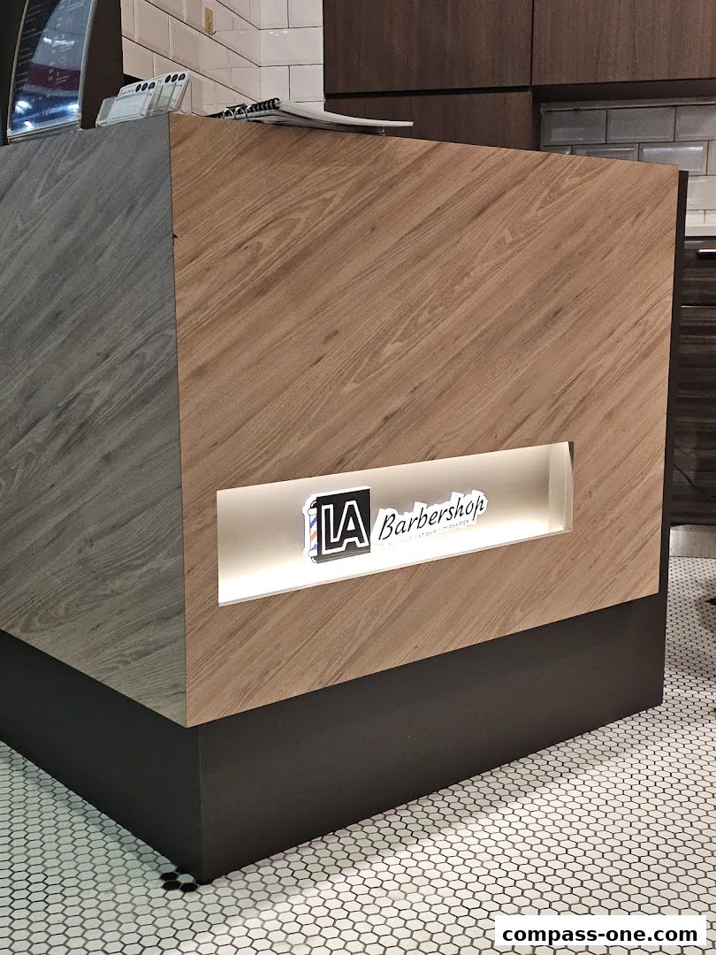 The reception counter of LA Barbershop with its logo illuminated.