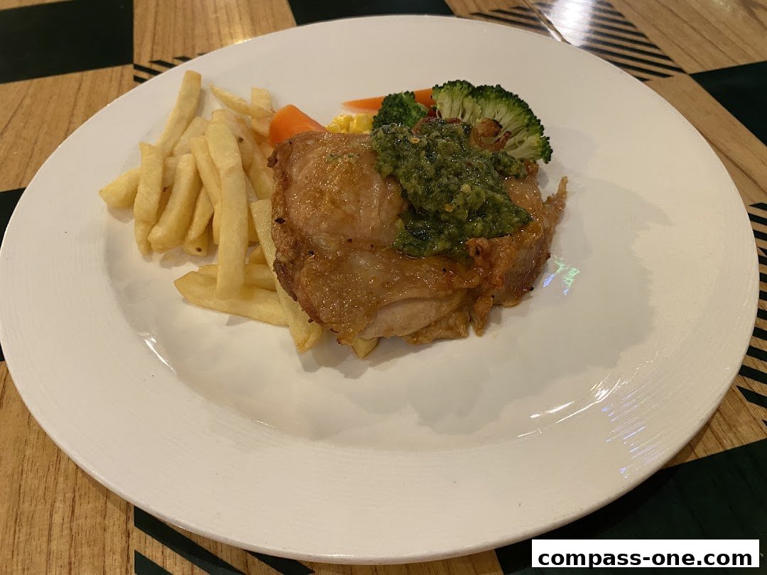 A plate of grilled chicken with fries, broccoli, and a green sauce.