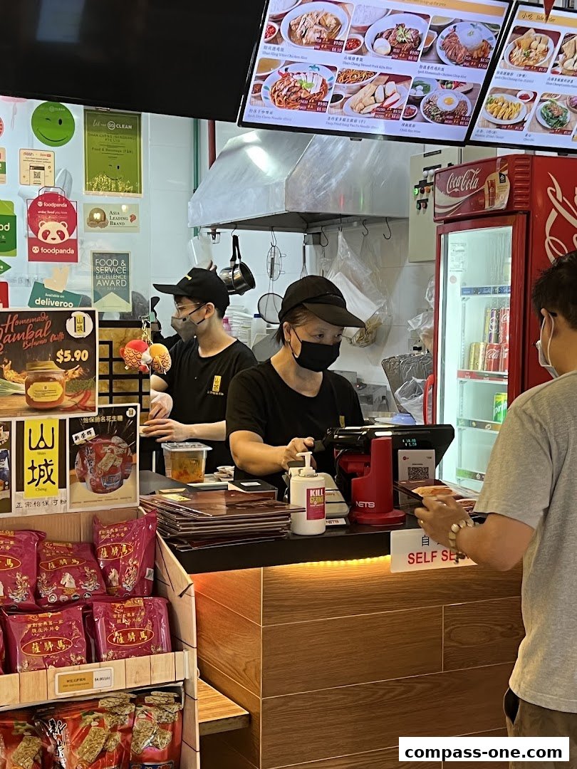 Staff serving customers at a counter with food displays and a Coca-Cola fridge.