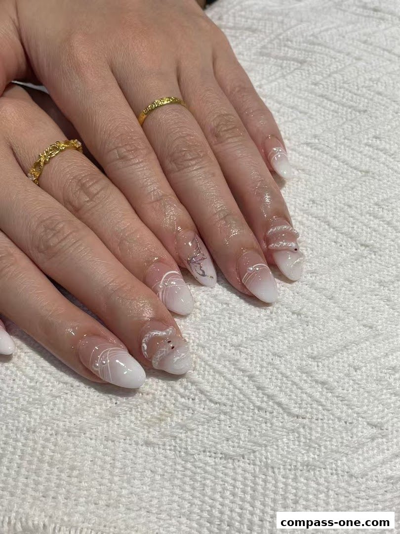 Close-up of hands with intricately designed white and clear nails, adorned with gold rings.
