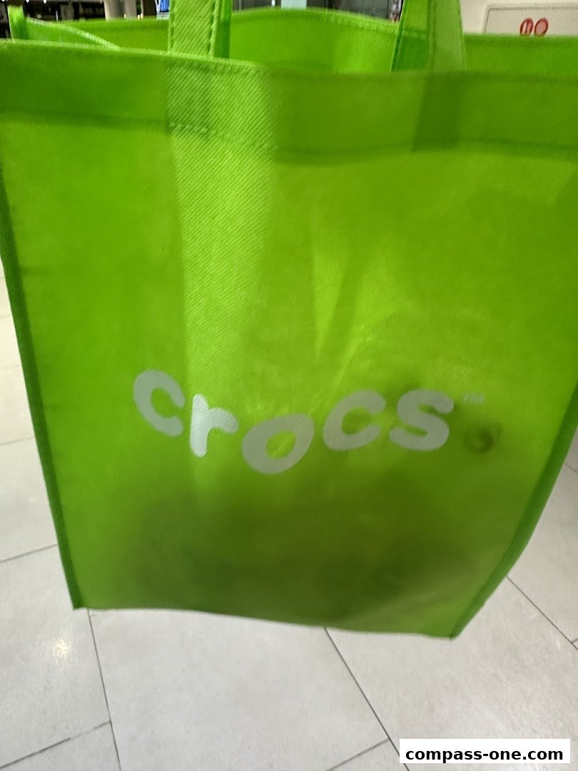 A bright green reusable shopping bag with the Crocs logo.