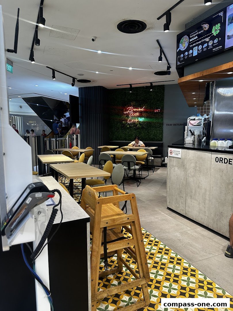 Interior of a modern eatery with tables, chairs, and a digital menu board.