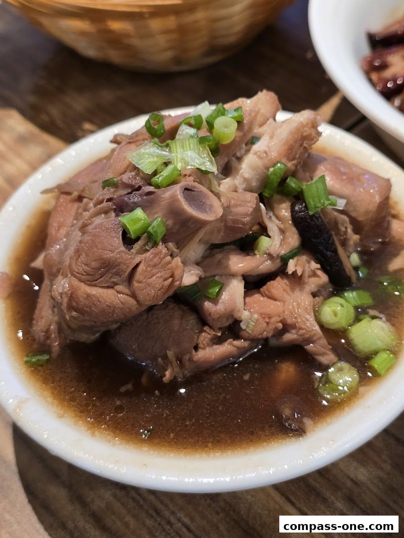 A close-up of a bowl of braised meat dish with chopped scallions.