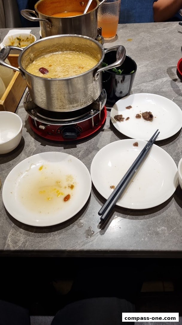 A table setting with a hot pot, plates, and chopsticks, suggesting a meal in progress.