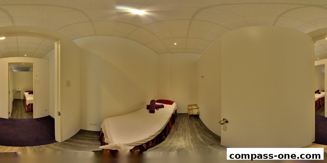Interior view of a spa room with a massage bed and a sink in an adjacent room.