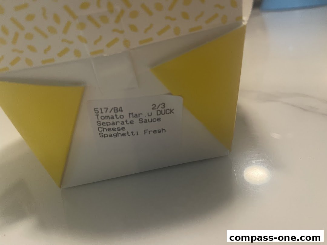 A close-up of a takeaway pasta box with printed text indicating the order details.