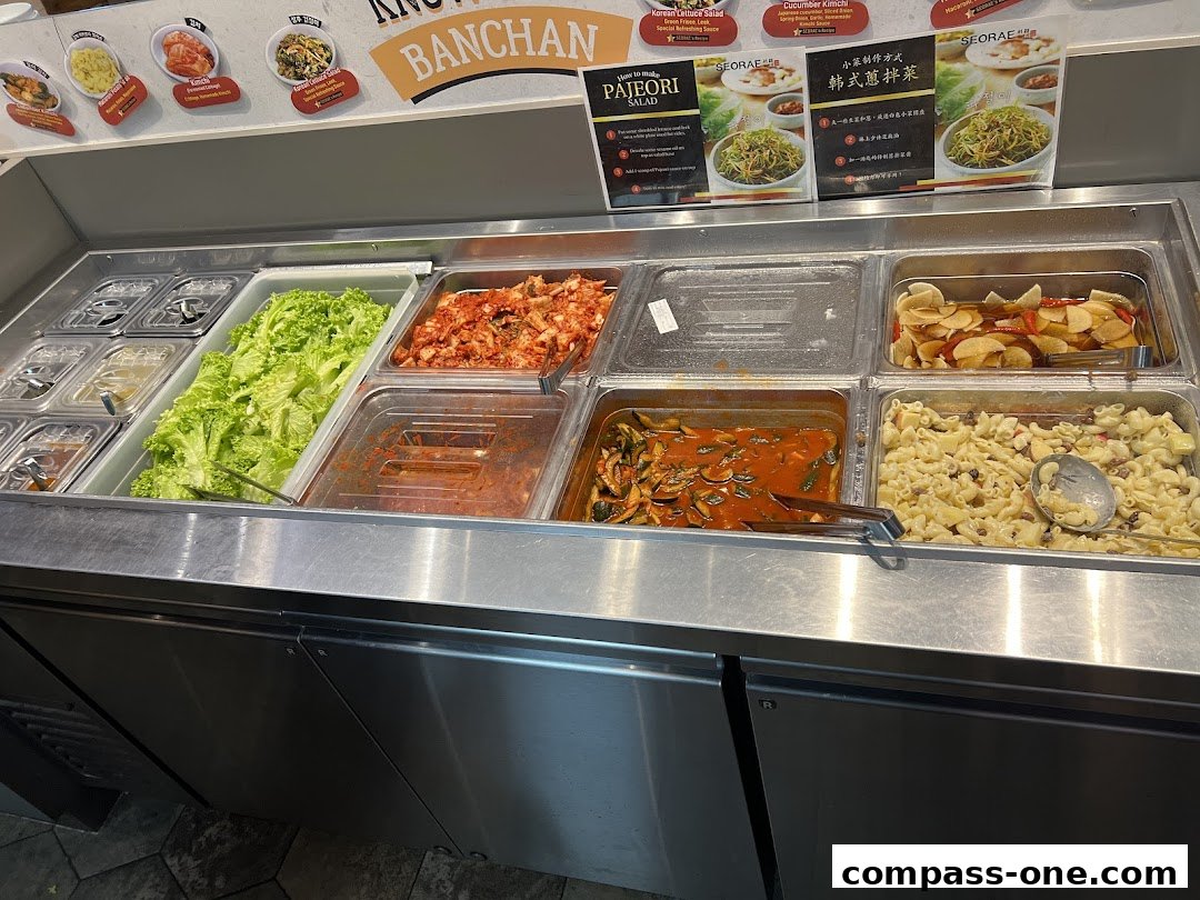 A display of various Korean banchan dishes, including kimchi, lettuce, and pasta salad.