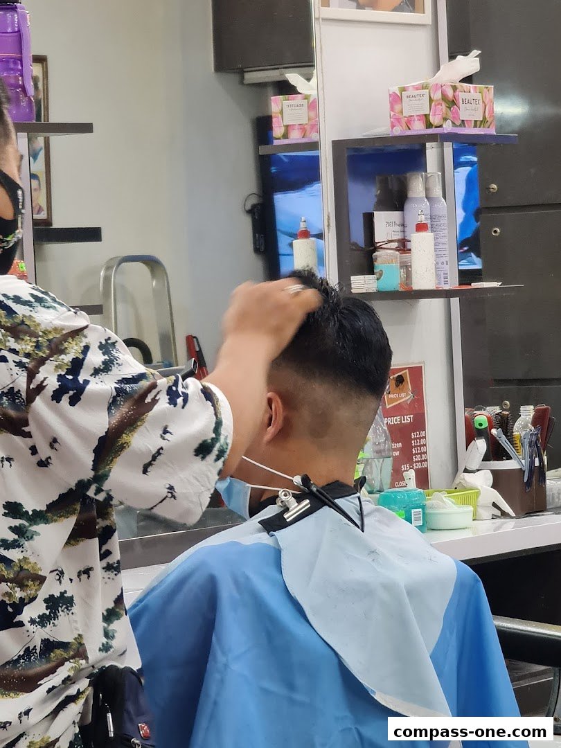A barber is giving a haircut to a customer in a salon.