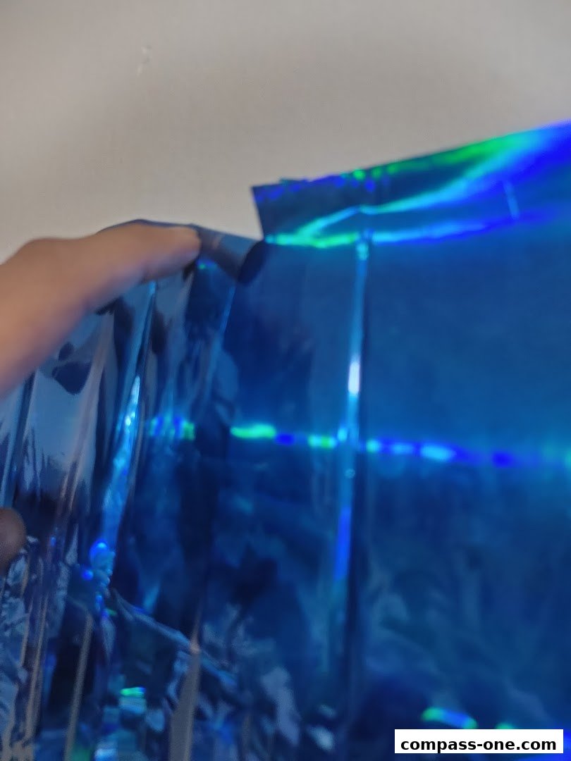 A hand holding a shiny blue holographic material with green reflections.