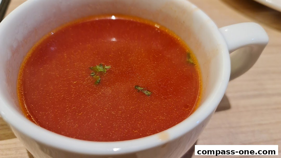 A close-up shot of a steaming bowl of tomato soup with a garnish of herbs.