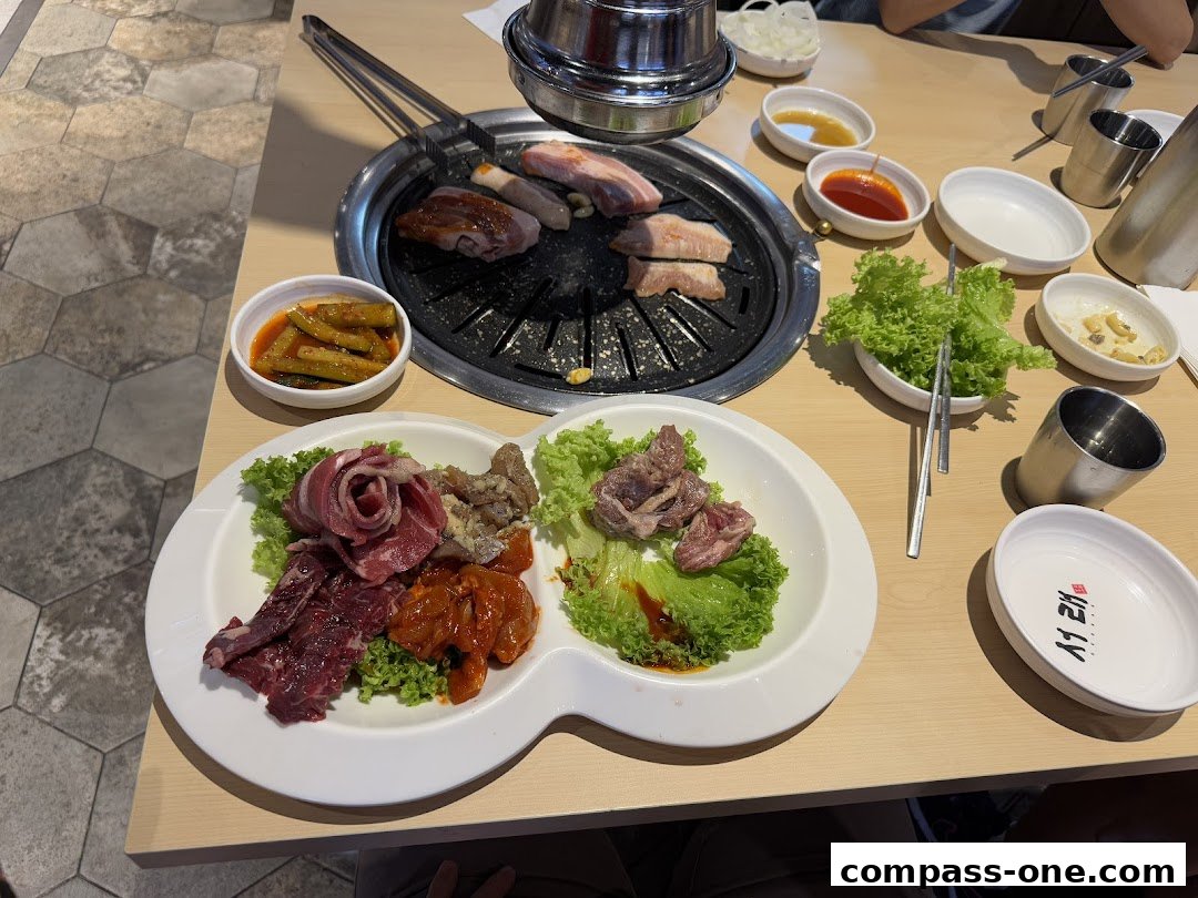 A table laden with Korean BBQ, featuring raw meats, grilled items, and various side dishes.