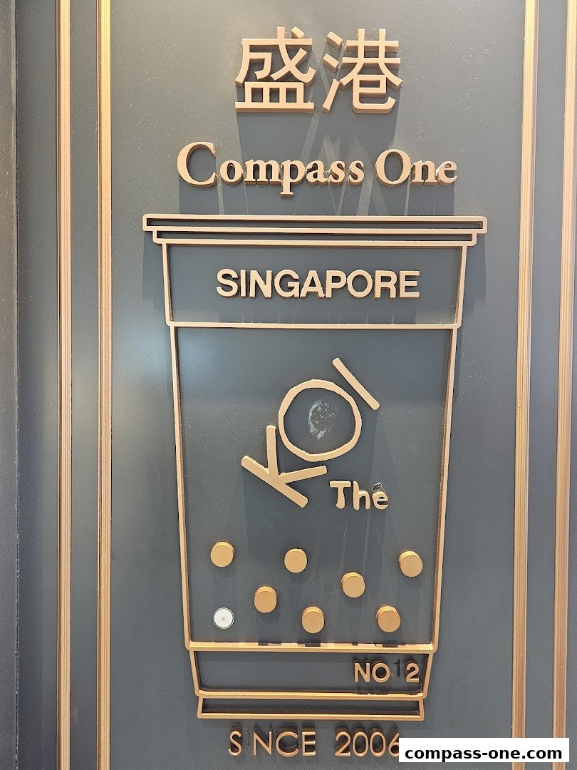A sign for KOI Thé at Compass One, Singapore, featuring a stylized bubble tea cup.