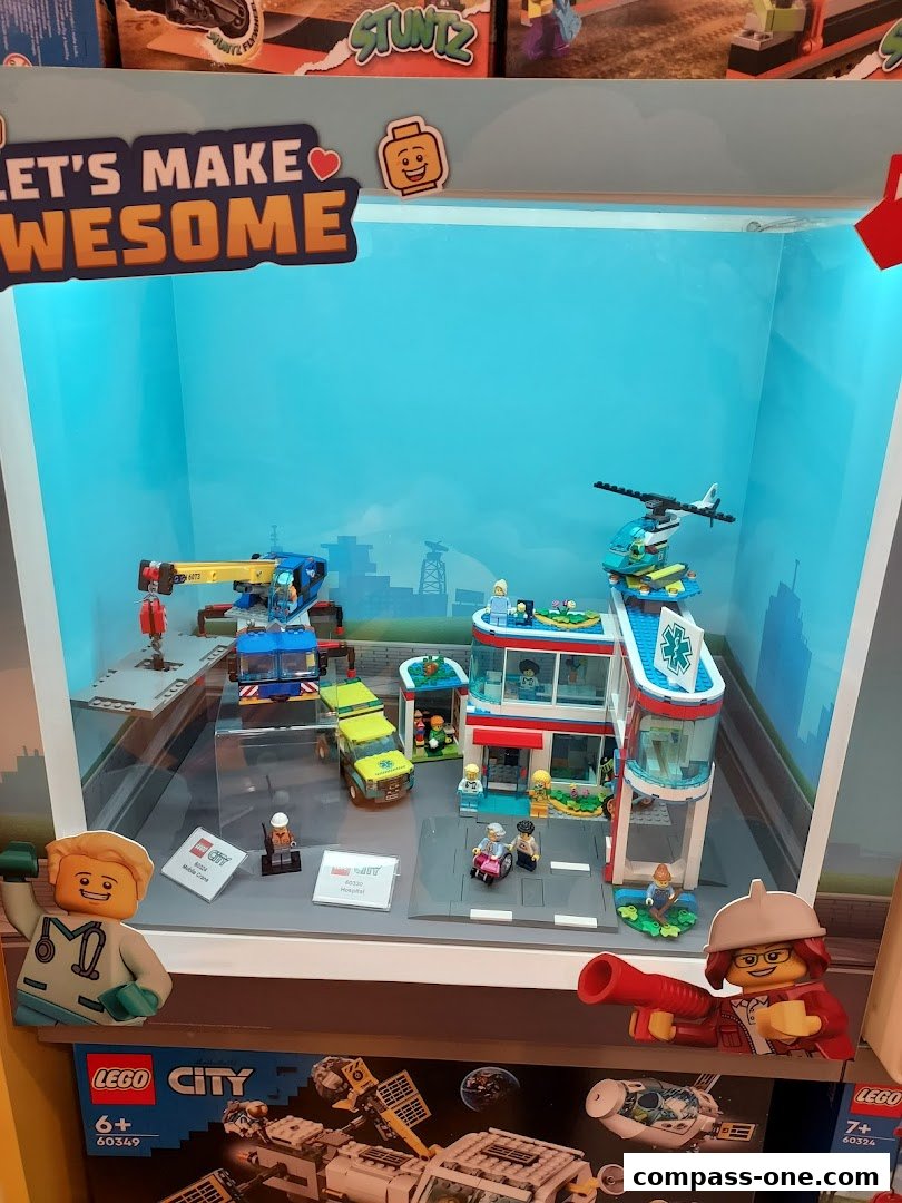 A LEGO City hospital and mobile crane playset displayed in a store window.
