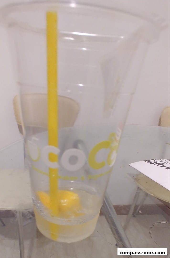 A clear plastic cup with a yellow straw and a slice of lemon inside.