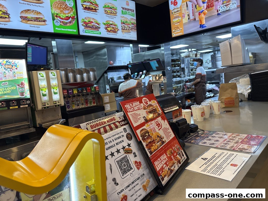 Interior view of a Burger King counter with menus, drinks dispensers, and staff in the background.