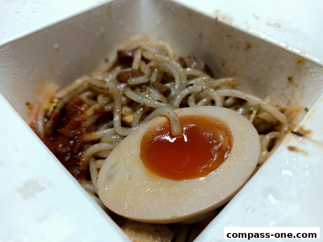 A close-up of a delicious noodle dish with a perfectly cooked soft-boiled egg.